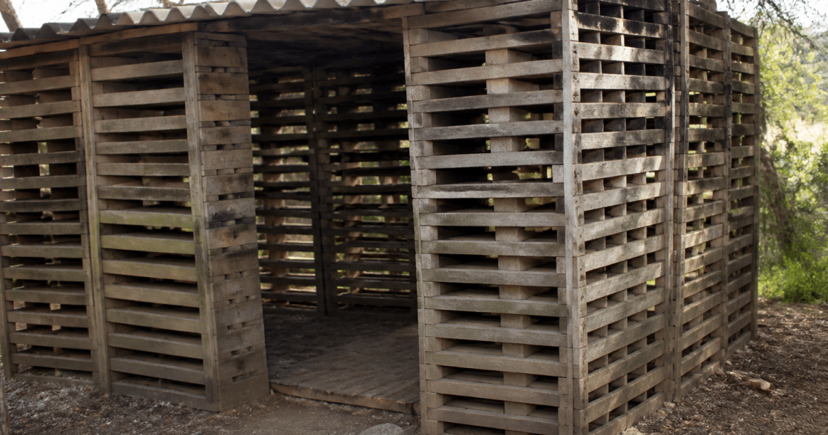 Palettes en bois empilees verticalement formant structure abri