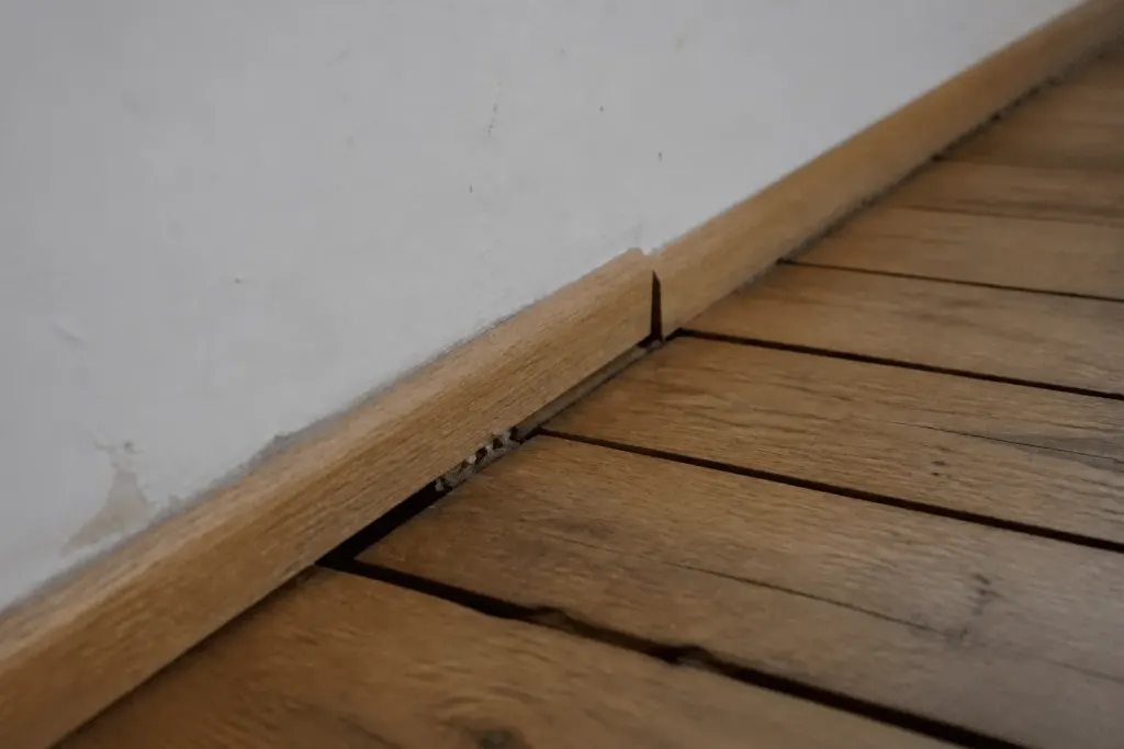 Baguette mal fixée directement sur parquet avec espaces visibles