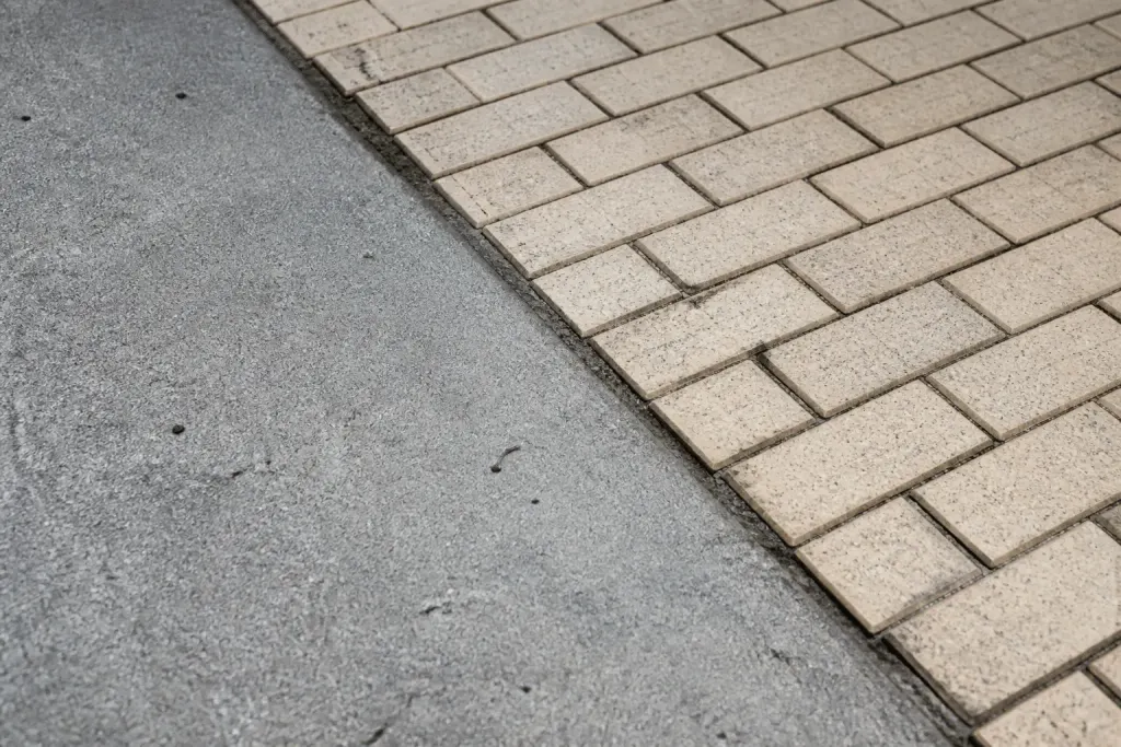 Surfaces de béton texturé gris et pavés beiges juxtaposés