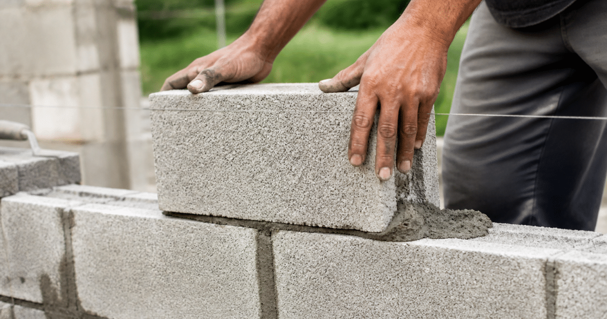Mains empilant blocs beton gris pour structure abri