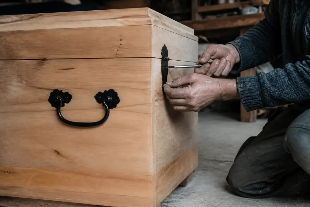 Mains installant charnières et poignees sur coffre bois