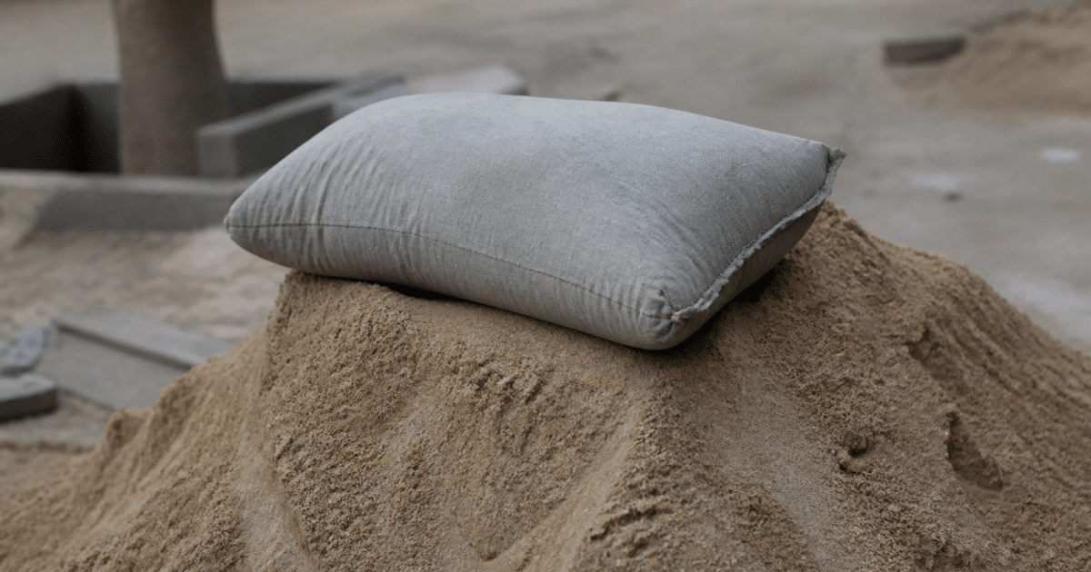 Sac ciment gris posé sur tas sable beige