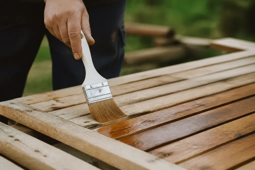 Pinceau appliquant traitement protecteur sur planches bois brutes