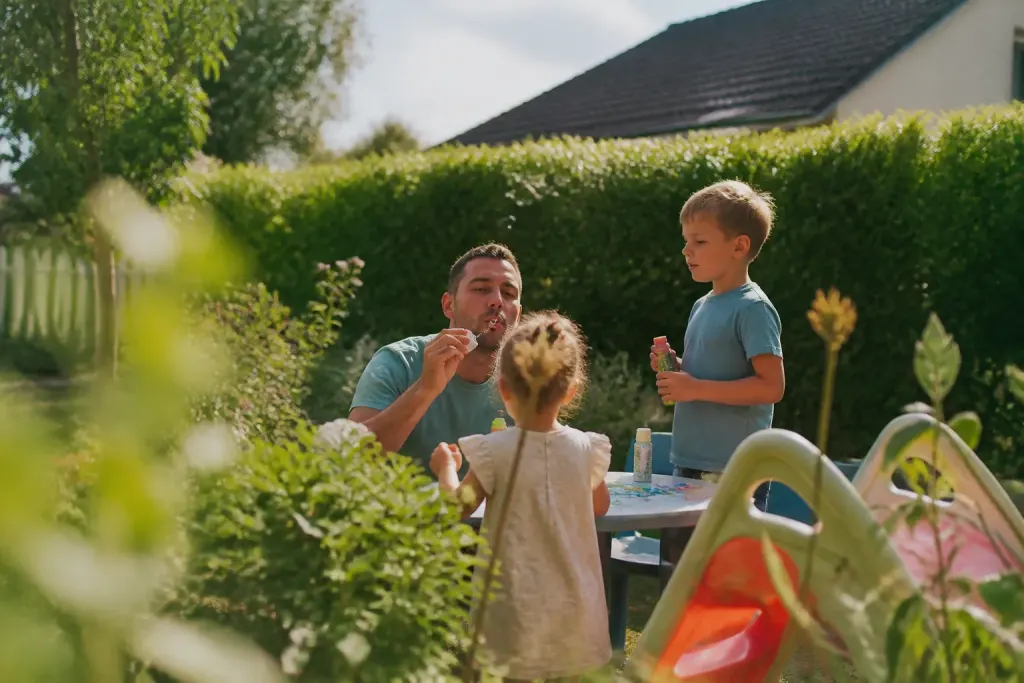 Famille et enfants jouant dans un jardin pavillonnaire